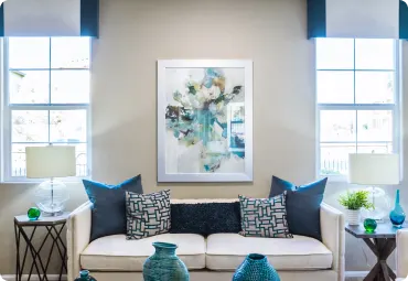 Bright living room with white sofa, blue accent pillows, and abstract wall art