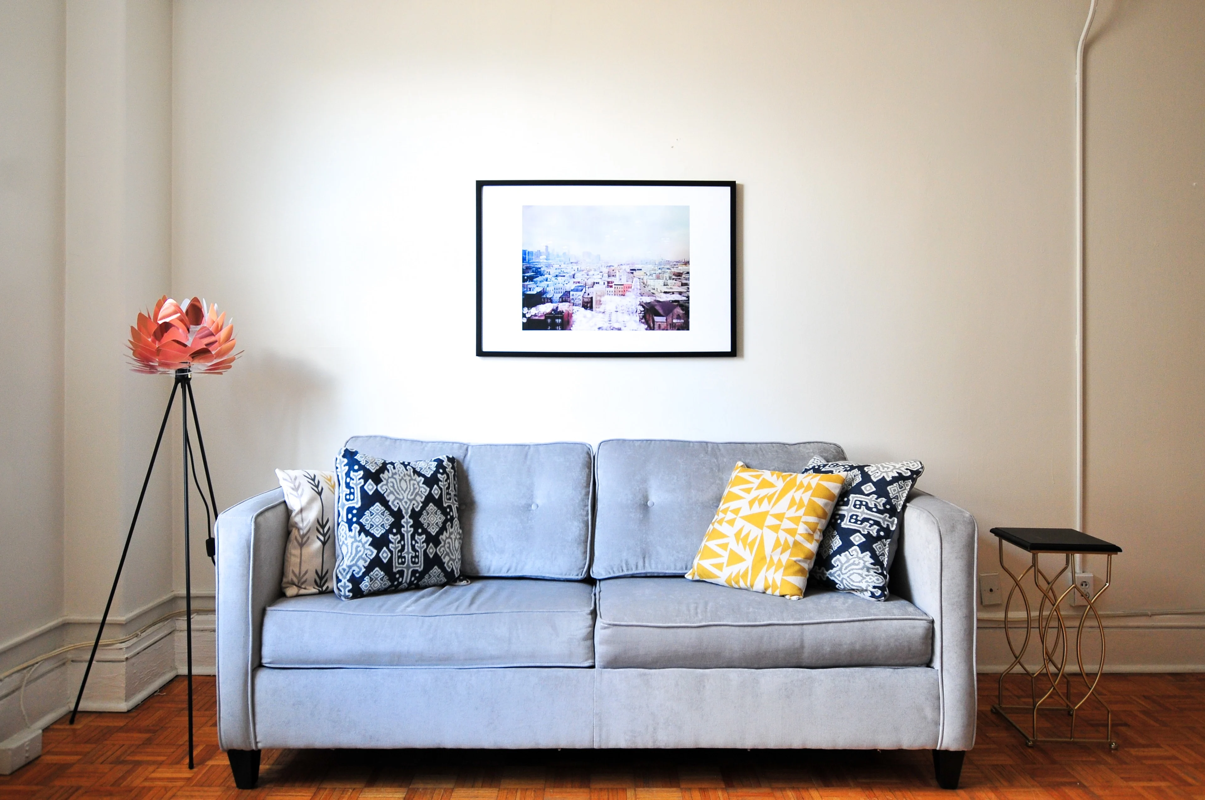 Cozy room with light gray sofa, patterned pillows, and framed wall photo